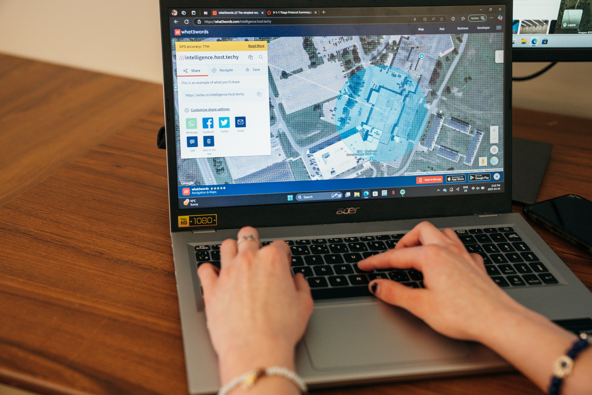 Close up view of a laptop showing an emergency services map. A womans hands are on the keyboard, with a bracelet on each arm.
