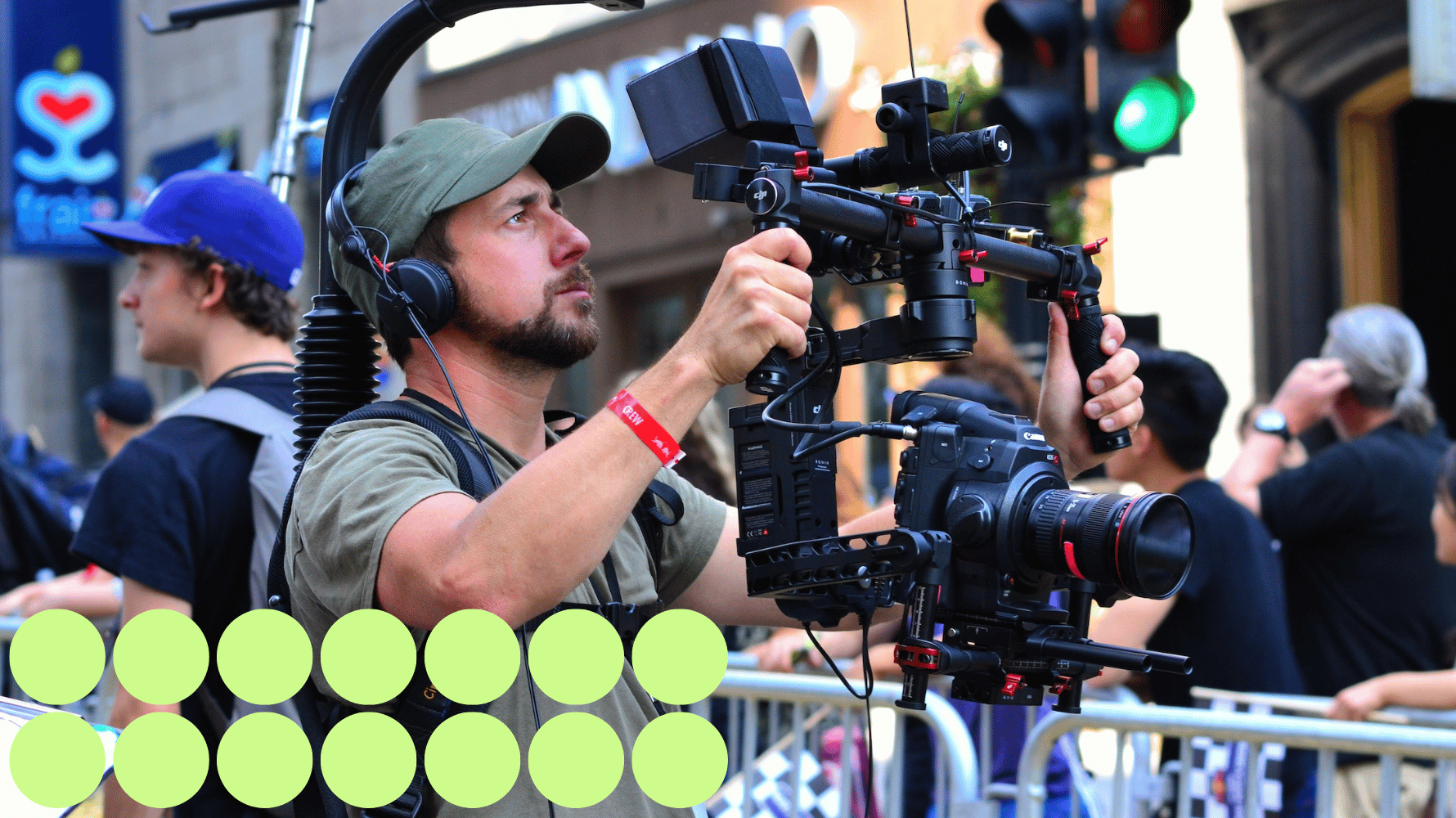 A film student is operating professional film equipment in a production. Fourteen green graphic circles are in the lower lefthand corner of the image.