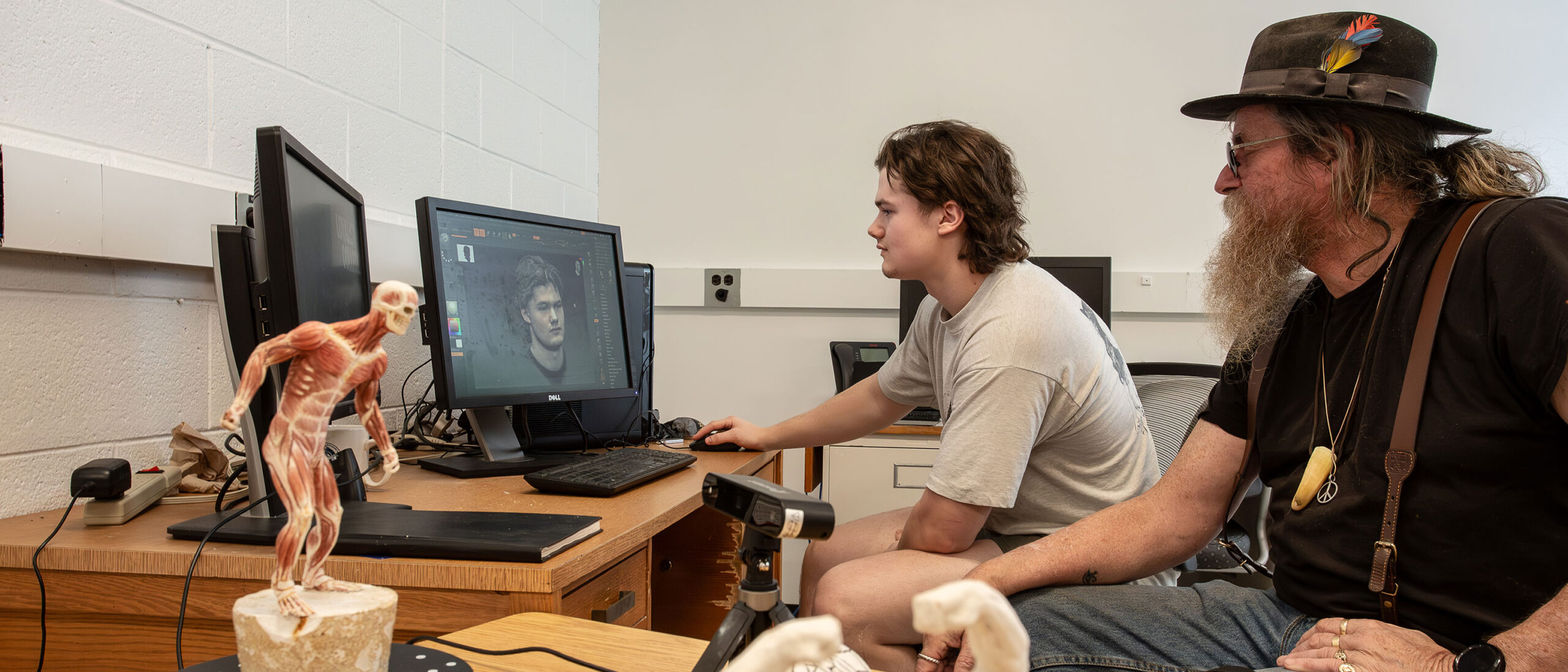 A student and professor are sitting next to each other working on an animation and game development project.