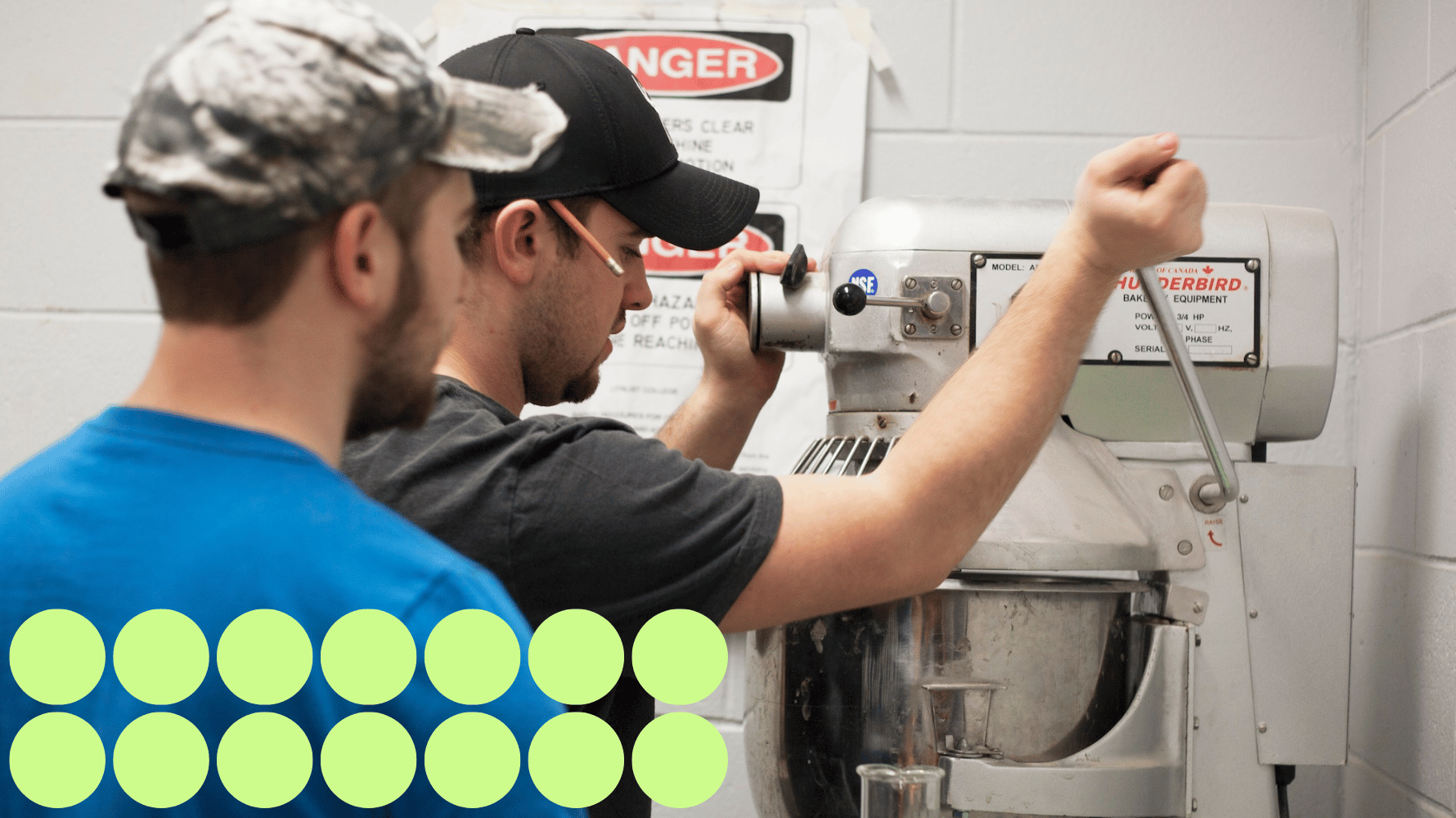 Two civil engineering technician students are looking at a mixer. One student is using the mixer while the other student is observing. Fourteen green graphic circles are in the lower lefthand corner of the image.