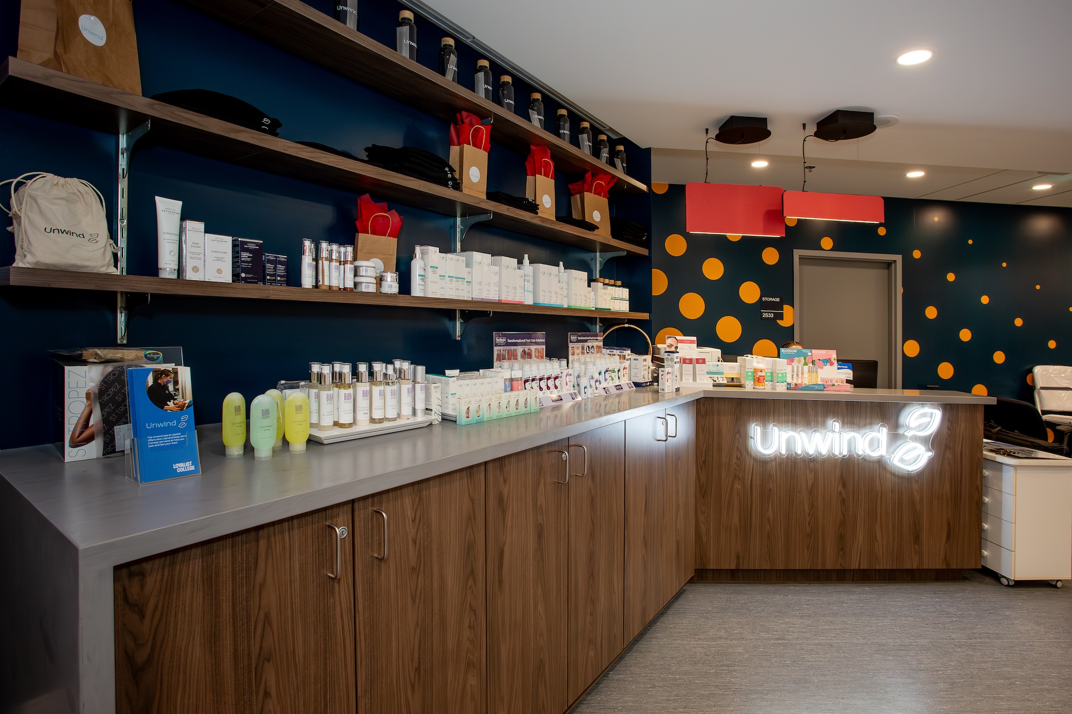 The reception desk of the Unwind Spa is shown, and along the side, products are displayed on the counter and shelves.