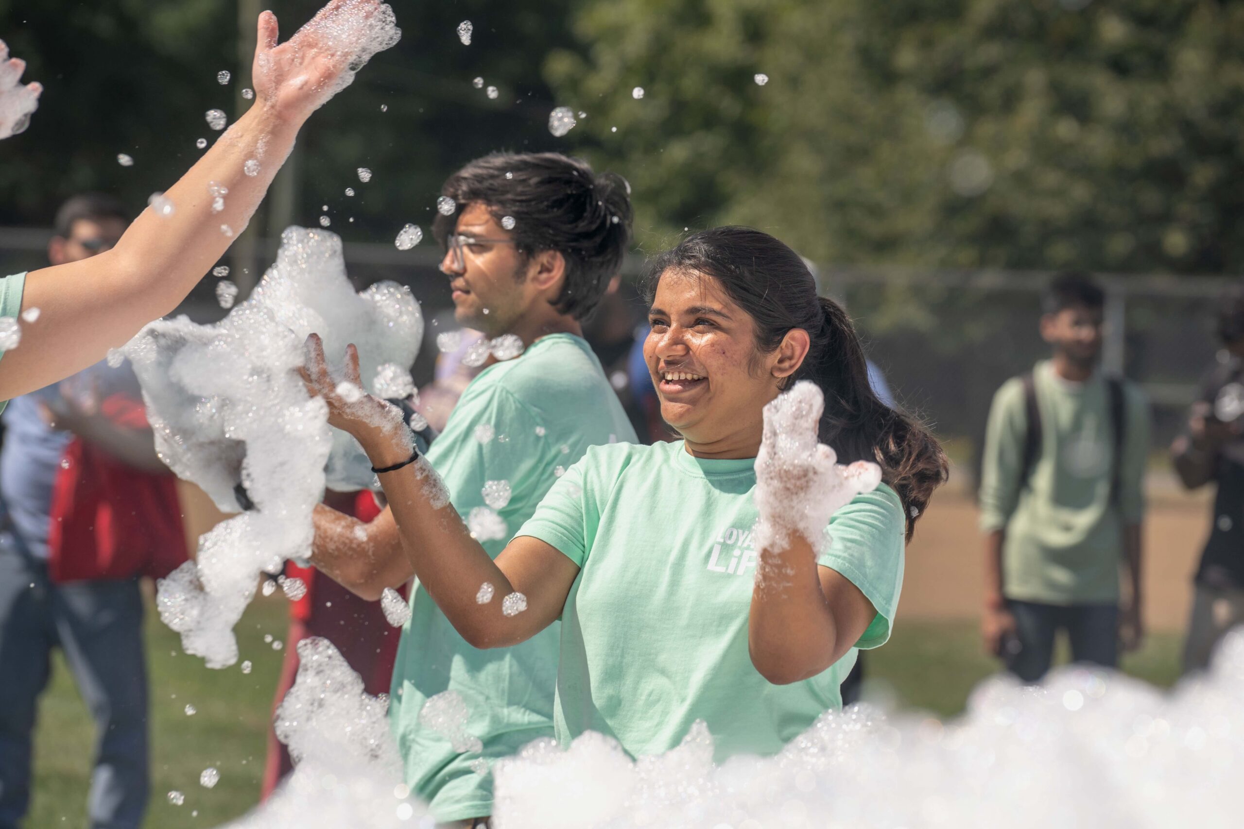 Students enjoying a fun moment during the foam party at Shark Watch, with smiles and laughter filling the air as they playfully interact with the bubbles.