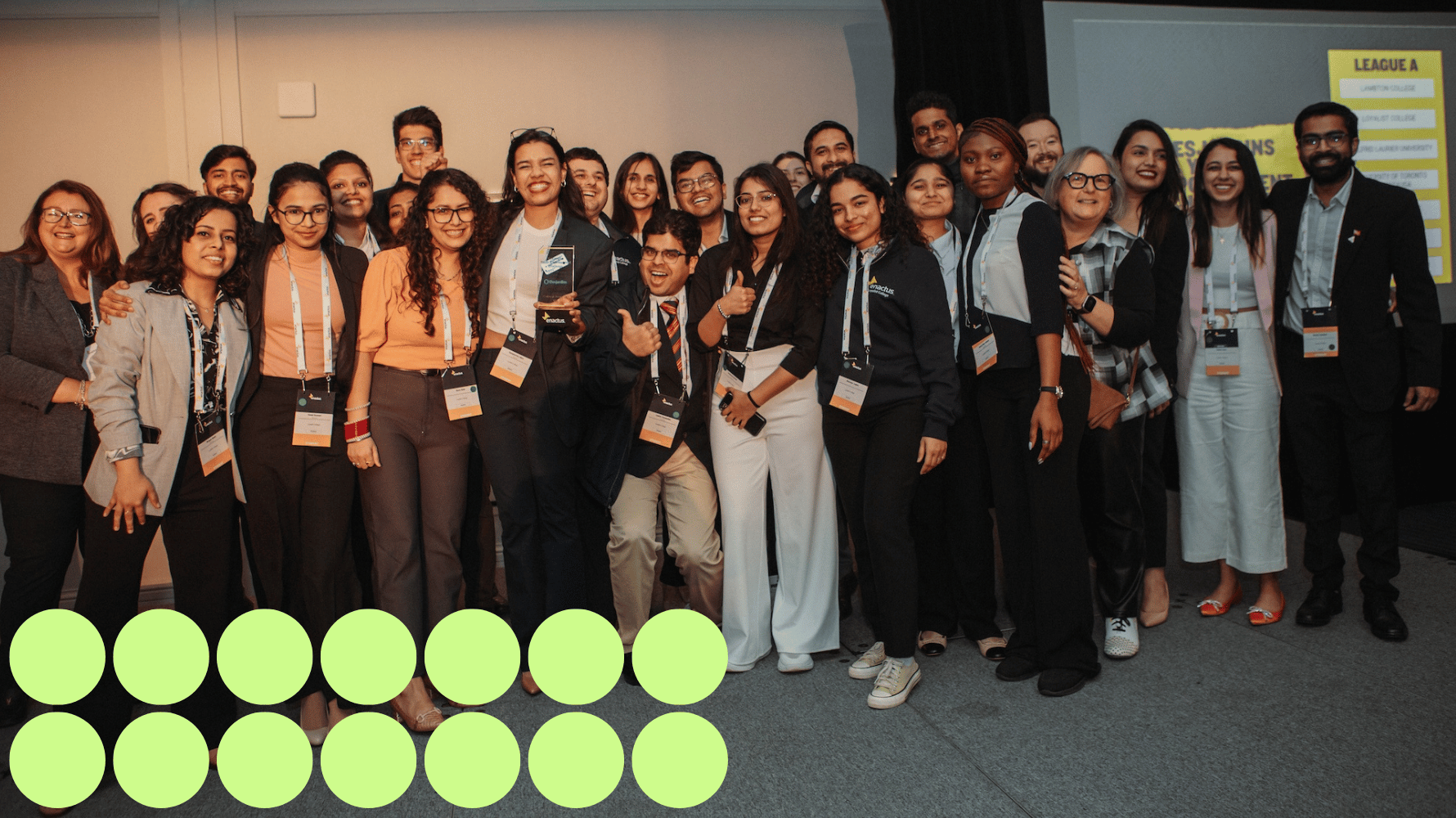 A group of smiling students in the Business program at Loyalist College. Fourteen light green graphic circles are along the bottom left of the image.