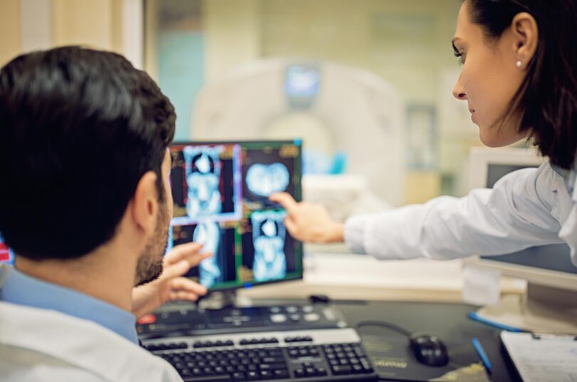 Two side profiles of two people are seen looking at a screen in the medical radiation technology program.