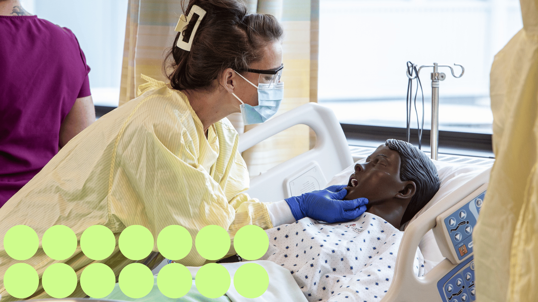 A student in the personal support worker program is working with a mock patient in a clinic setting. The student is checking the mock patient's mouth with their hand. Fourteen green graphic circles are in the lower lefthand corner of the image.