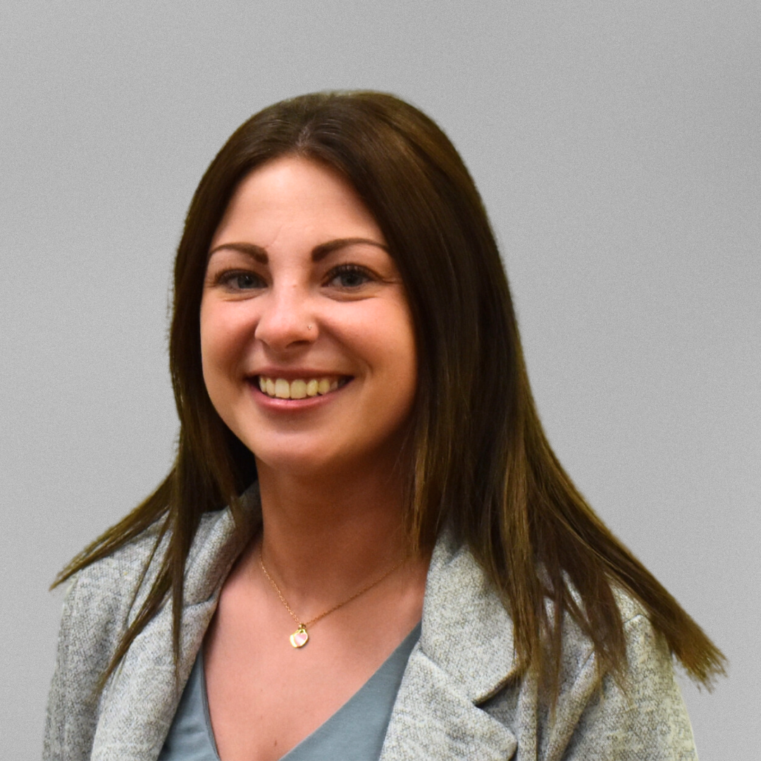 A headshot of Taylor Dumont in front of a grey background.