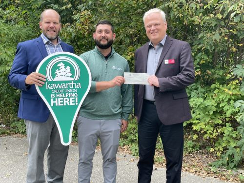 Loyalist Acting President, Mark Kirkpatrick, posing with two staff members of Kawartha Credit union. One is holding a sign with the Kawartha Credit Union logo and the other is holding a cheque with Kirkpatrick.