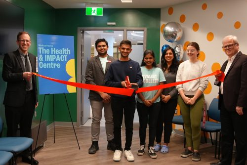 A group of people in the newly opened Health and Impact Centre at a ribbon cutting ceremony.