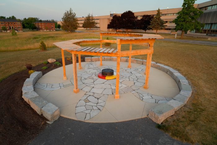 A drone shot of the A’nó:wara Learning Circle behind Loyalist College, in the background are residence buildings and part of the college.