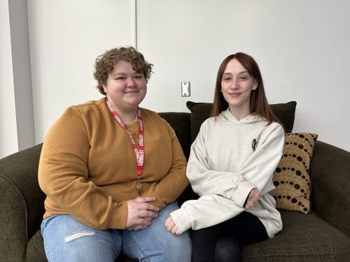 Dual Credit students at Loyalist, Brice Hass and Demona Boyer, sitting on a coach smiling at the camera.