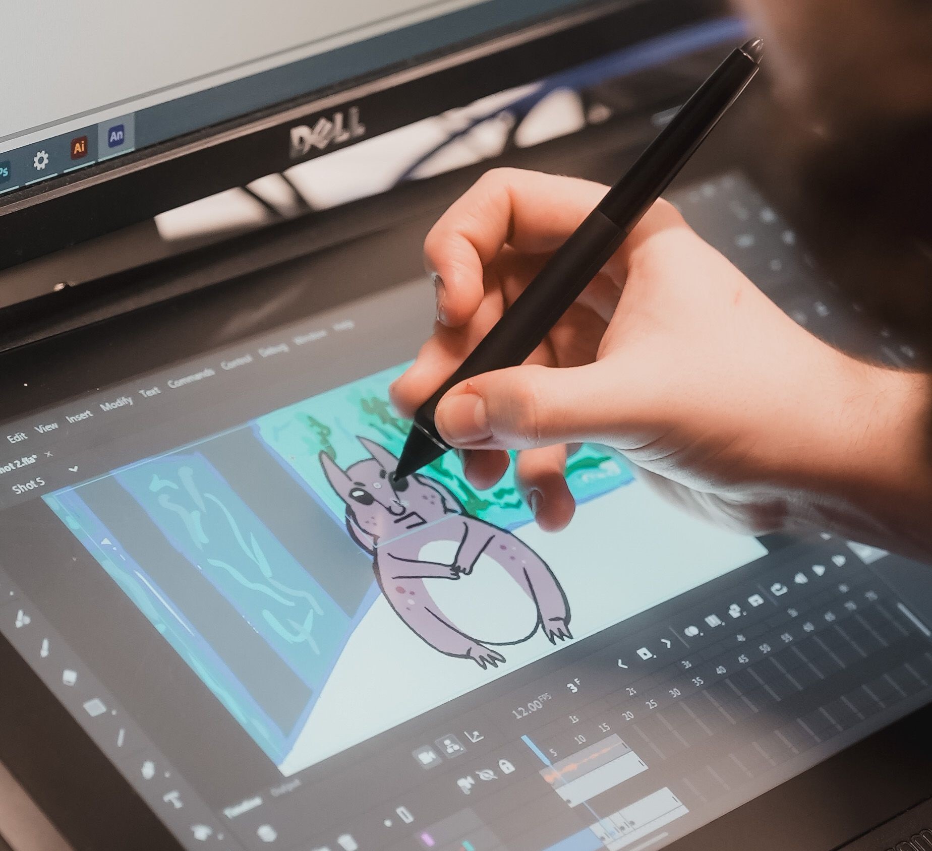 A closeup image of a hand holding a design pencil and drawing on a tablet. The picture is an animation of an animal.