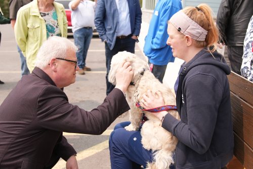 Mark Kirkpatrick, Loyalist President and CEO, knelt in front of a woman and her dog, petting the dog.