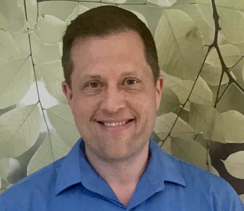 Headshot of Barry Weese, the newly appointed Dean of Leadership, Learning and Academic Excellence. The background is a leaf and branch wallpaper.