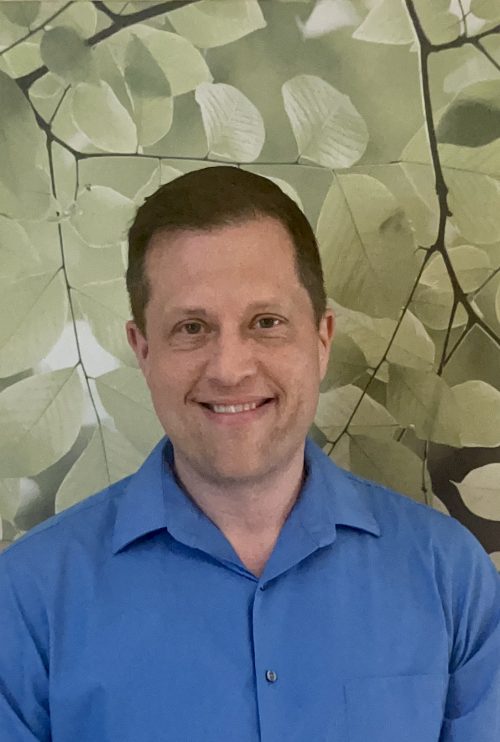 Headshot of Barry Weese, the newly appointed Dean of Leadership, Learning and Academic Excellence. The background is a leaf and branch wallpaper.