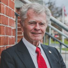 A headshot of former Port Hope Mayor, Robert Sanderson outside against a red brick building.