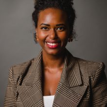 A headshot of Shamsa Hassan, founder of Afiya Beauty, in front of a dark grey background.