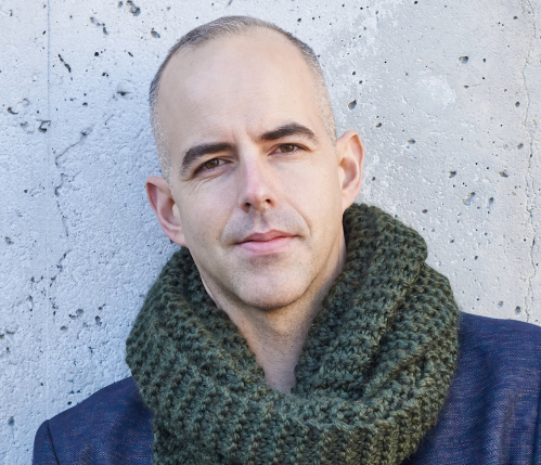 A headshot of Janak Alford, in front of a concrete background.