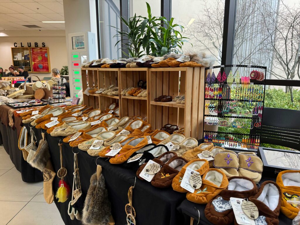 A table at the Indigenous Arts Festival displaying a selection of handcrafted goods, including moccasins and beadwork.