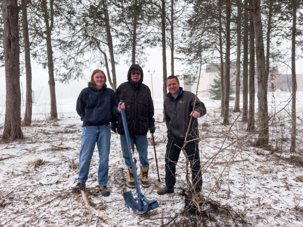 The Titan Tree Puller project team of Loyalist College student Alicia Cannon, professor Jeremy Braithwaite, and Peter Fisk stand with the prototype in spring 2025.