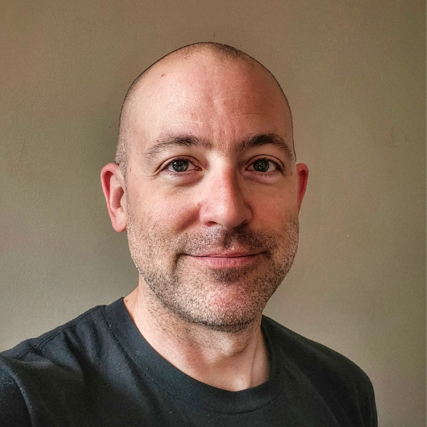 Loyalist College Student Advisor Cory Mestre smiles at the camera, sitting in front of a beige background.