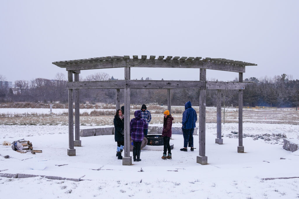 Loyalist College students and staff gather around a winter fire at the A’nó:wara Learning Circle.