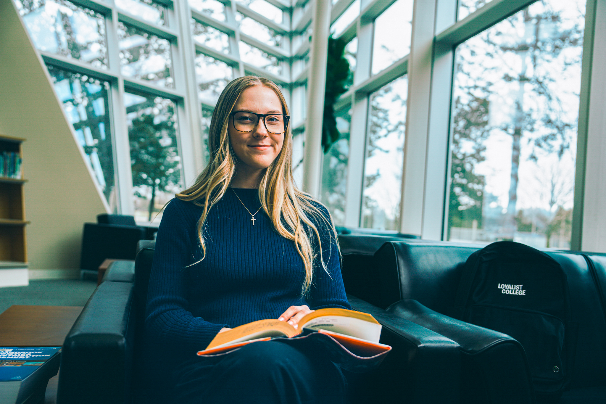 Student sitting in a library area with an open book on lap