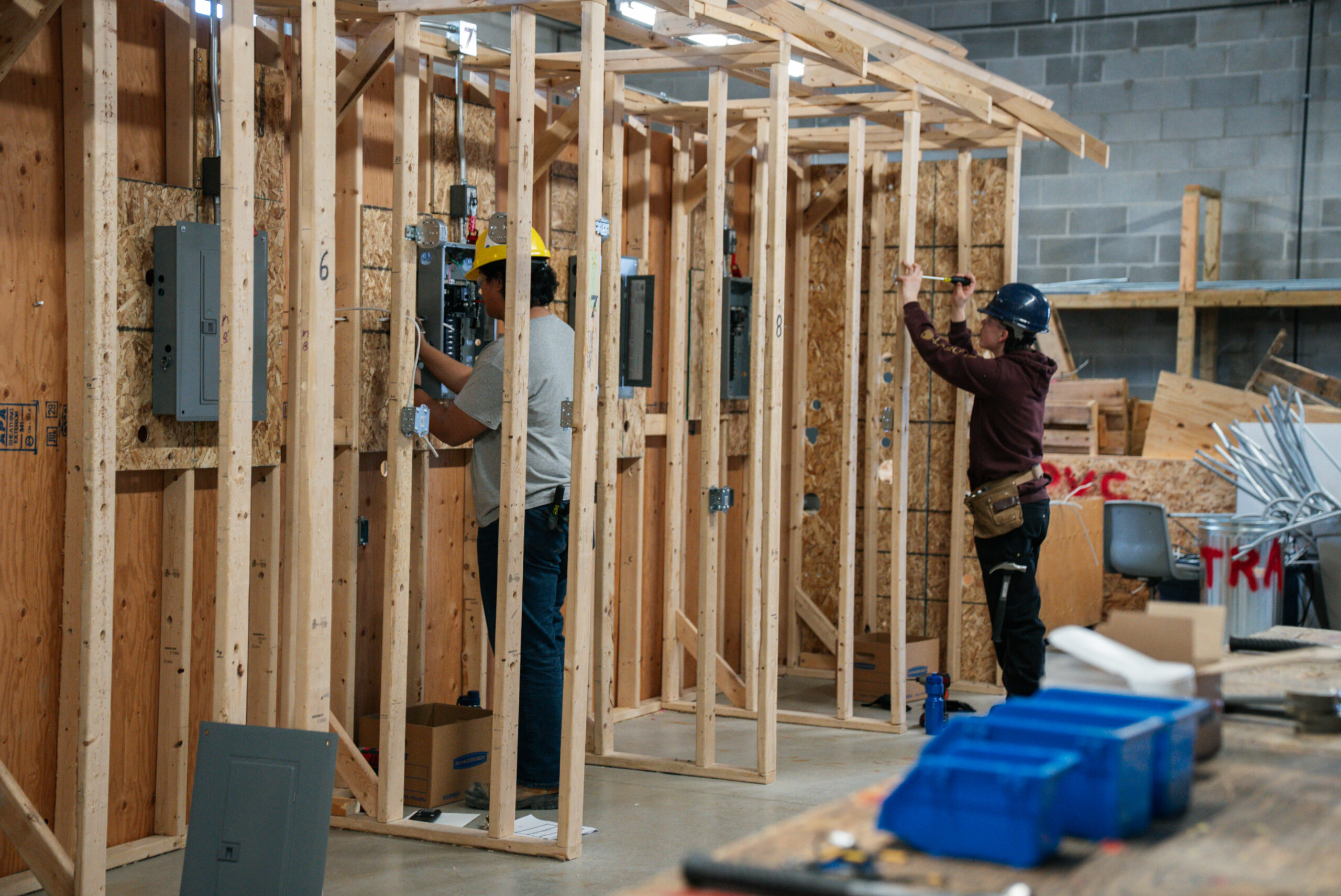 Two electrician students learning to wire a building unit.