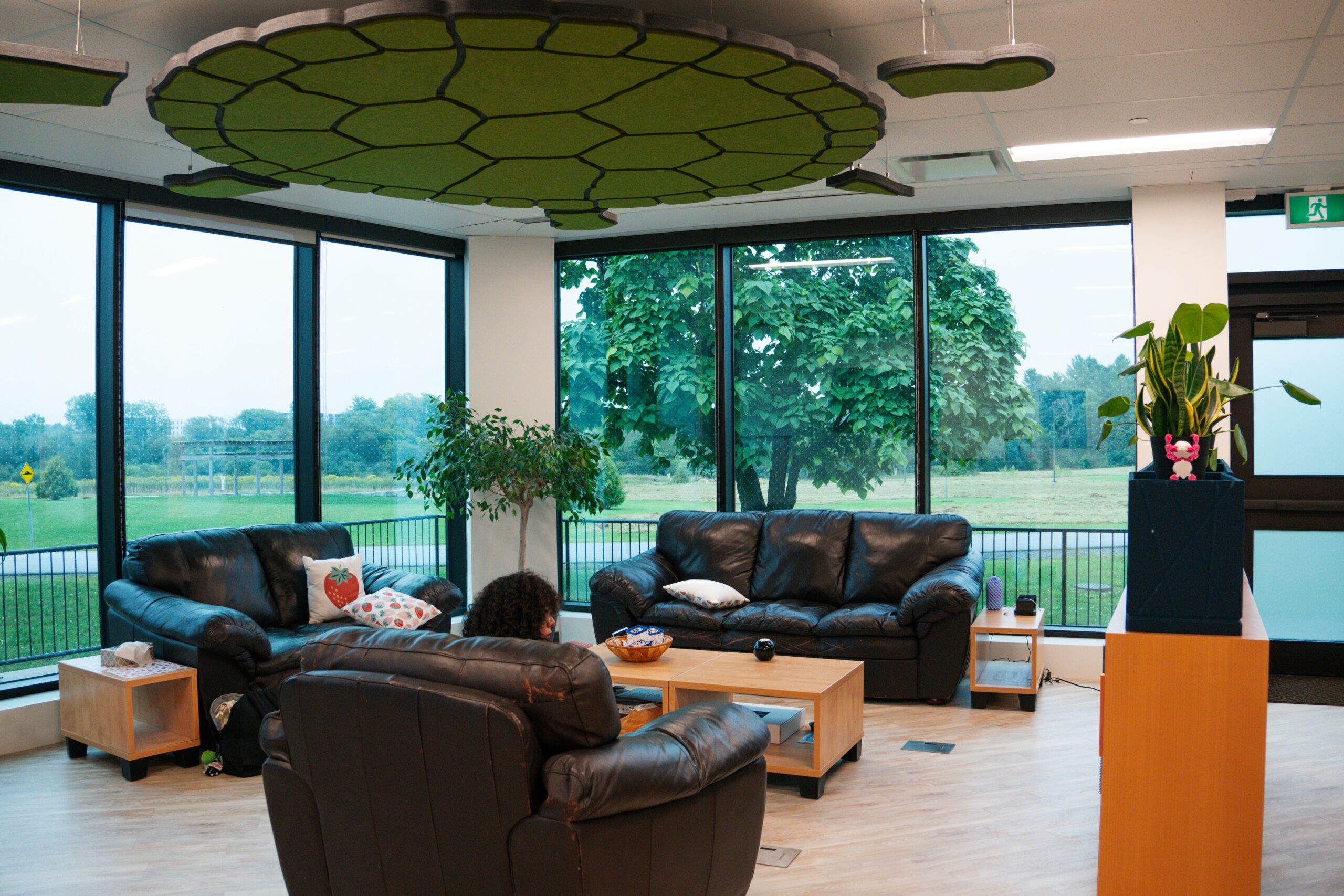 A student sitting in the Indigenous Centre lounge area with couches, plants and large windows overlooking campus.