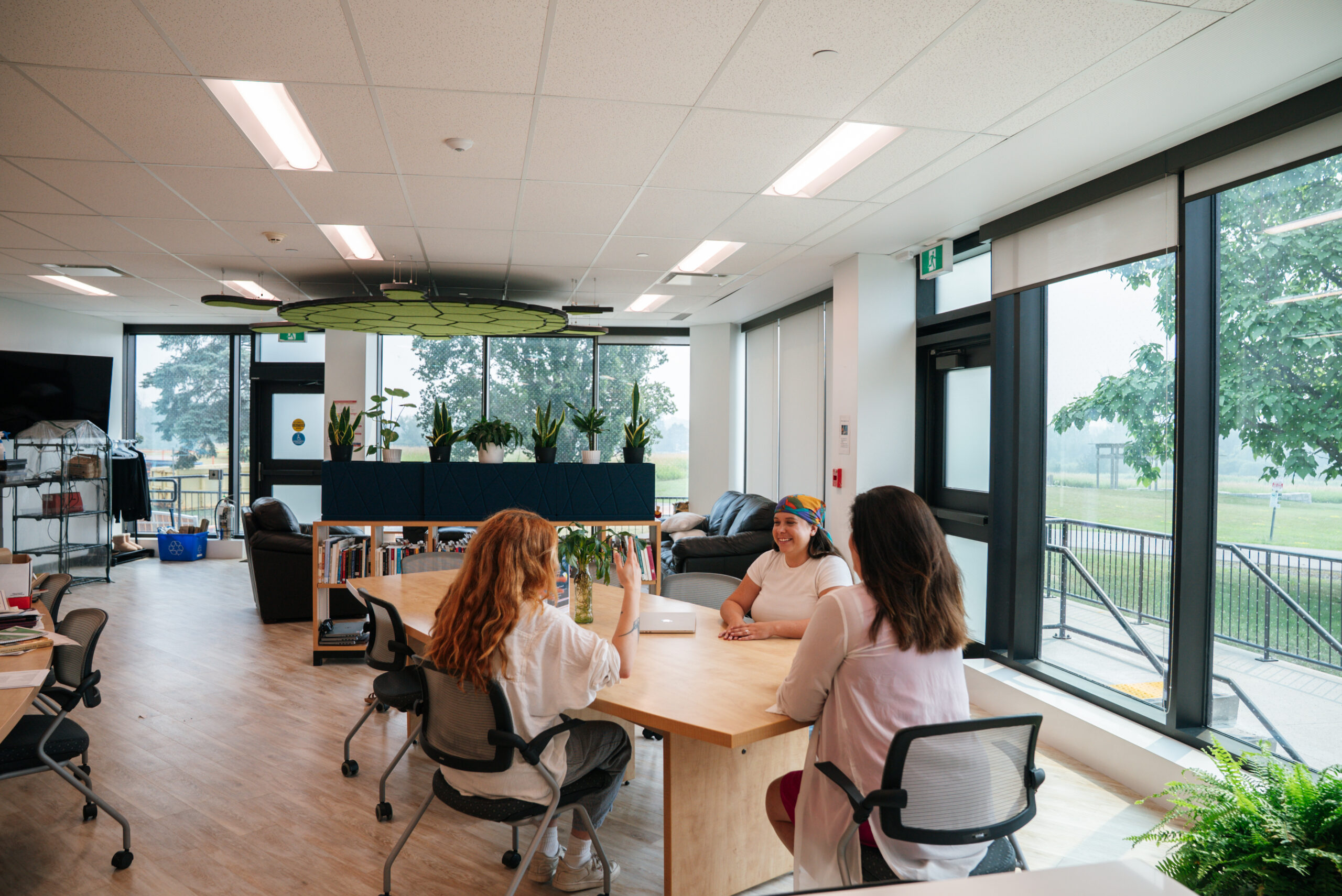 Three people talking around a table in the bright Indigenous Centre.