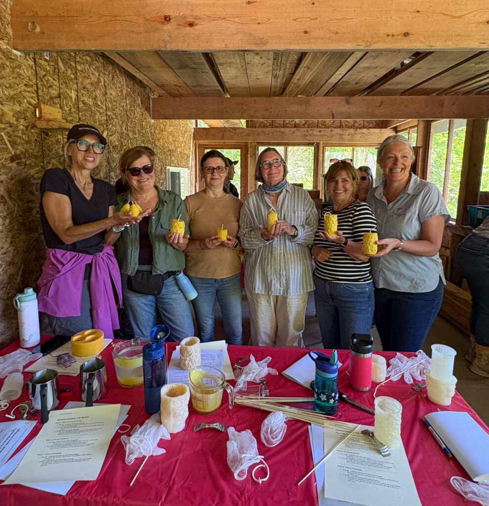A group of six adults shows their handmade beeswax candles during a Loyalist College Arts Experience beekeeping course.