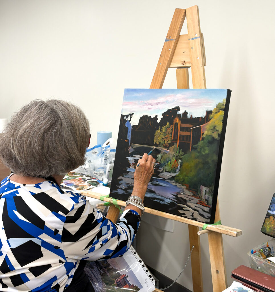 A woman with short, grey hair participates in a painting class offered by the Loyalist College Arts Experience