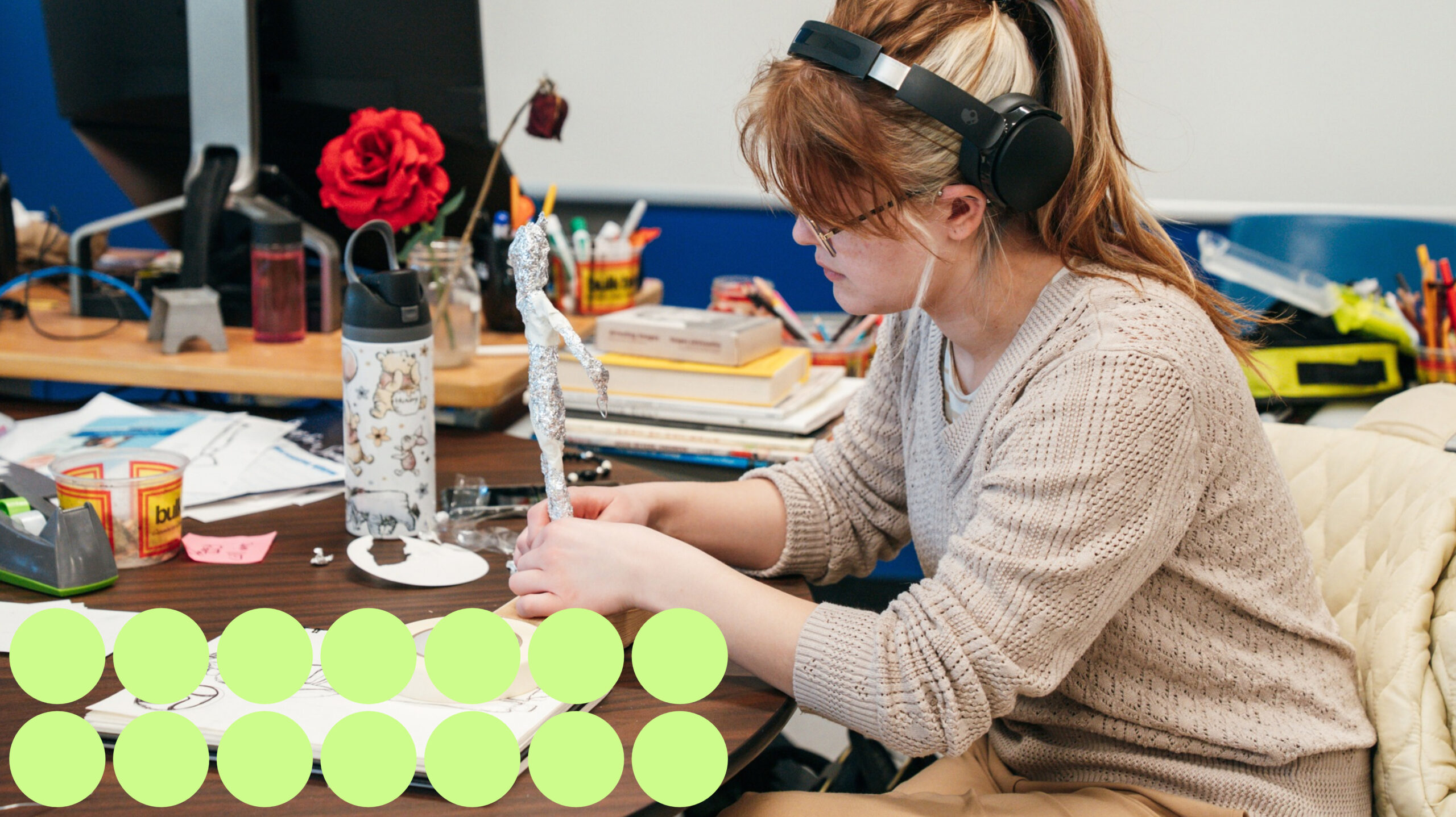 The Art and Design Foundations program student creating art. Girl wearing black headphones while focusing on art project.