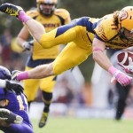 KINGSTON, Ont. (05/10/13) - Queen's University Gaels player Giovanni Aprile, 11, flies in the over Wilfrid Laurier University's Golden Hawks' Benjamin Millar, 13, during Queen's Homecoming game. Queen’s Gaels had a 40-34 victory over the Wilfrid Laurier’s Golden Hawks. Photo by Hannah Yoon