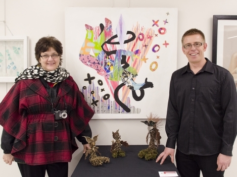 Robert Kranendon k, Coordinator of the Art and Design Foundation Program at Loyalist and Carol Bauer, artist and Members' Services Officer, Quinte Arts Council, pose in front of the artwork of two graduates of the program, Tiffany Jones and Ricardo Forbes. 